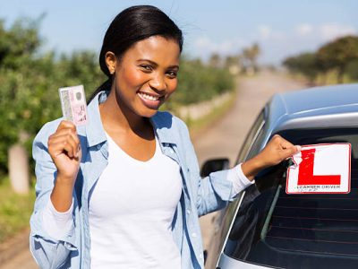 african woman removing learner driver sign after getting her driving license